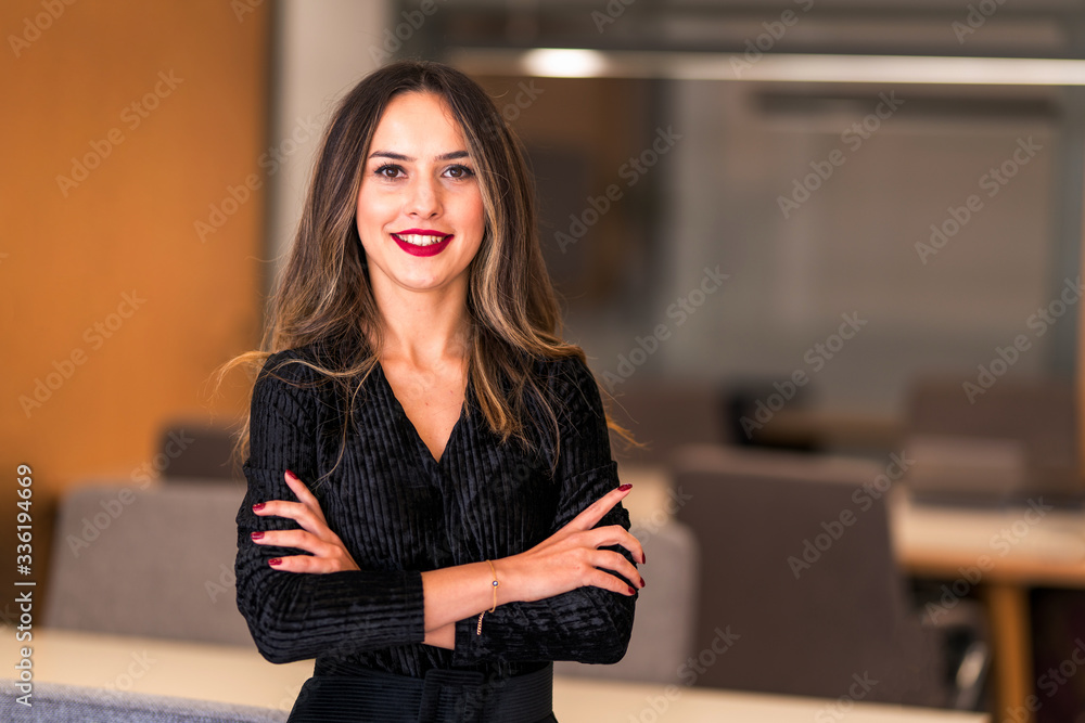 A smiling professional female executive stares into the camera with her standing arms tied. A smiling professional female executive stares into the camera with her standing arms tied.