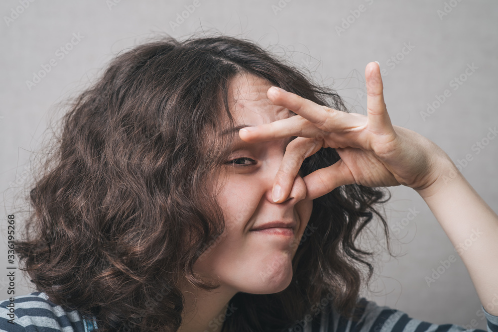 The woman closed her nose from the stench, bad smell. Gray background The woman closed her nose from the stench, bad smell. Gray background