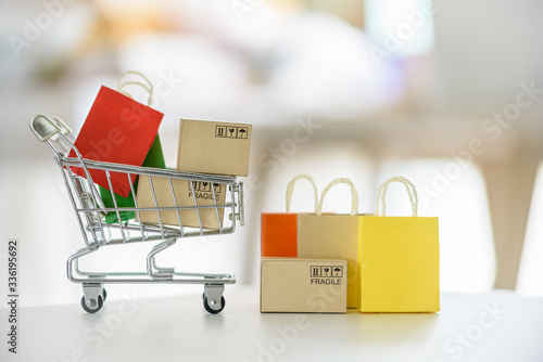 Online shopping / e-commerce and customer experience concept : Shopping cart with boxes, colored shopping bags on a table, depicts consumers / buyers buy or purchase goods and service from home