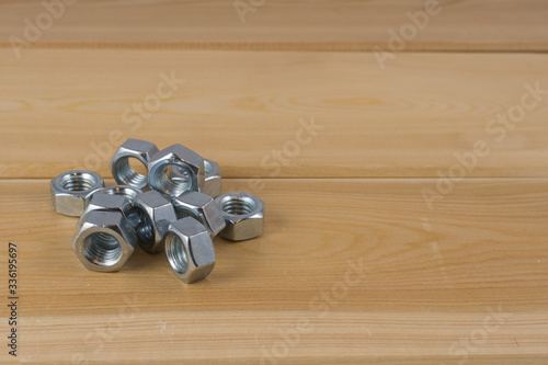 Metalowe nakrętki ułożone na drewnianej desce