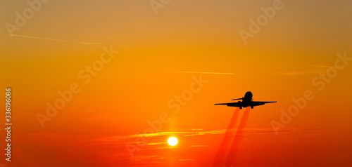 Airplane taking off at sunset. Silhouette of a big passenger or cargo aircraft, airline. Transportation. © Sergey Fedoskin