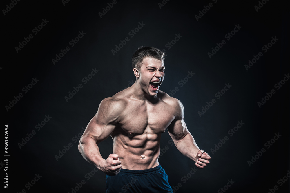 Sexy young athlete posing on a black background in the Studio. Fitness, bodybuilding