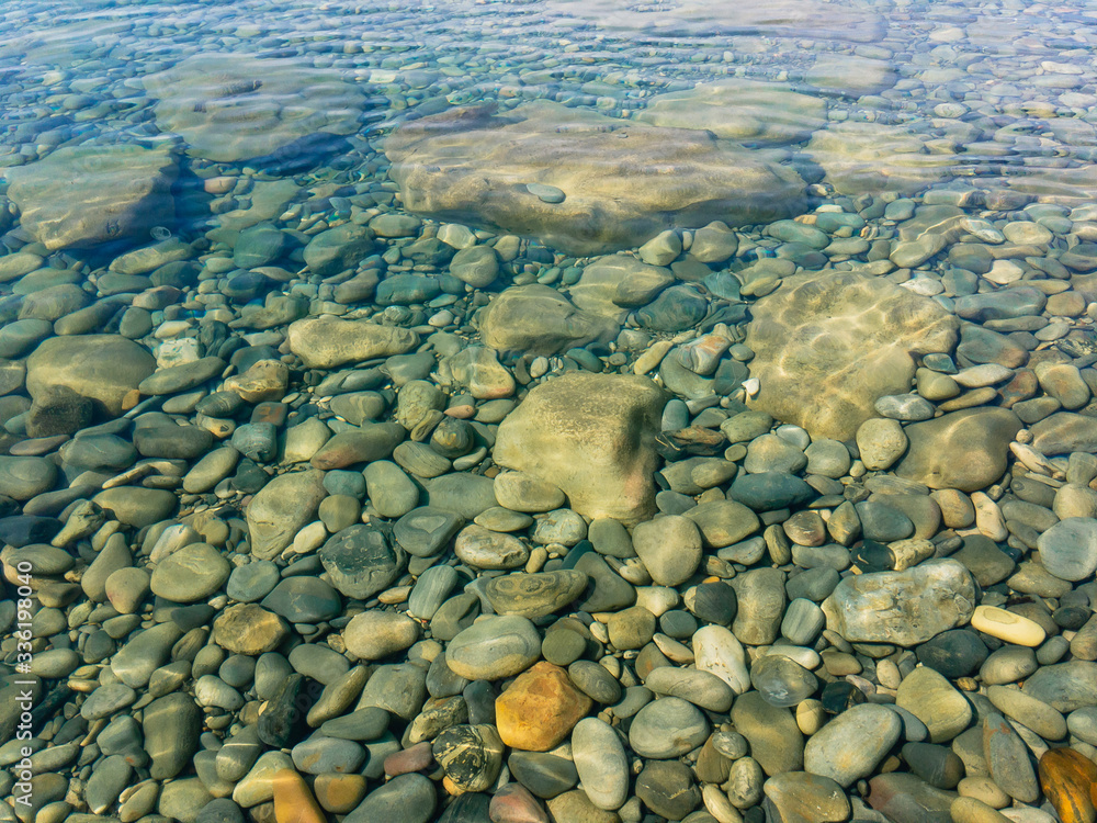 The stony bottom of the sea covered by transparent greenish water with glare of the sun. The stony bottom of the sea covered by transparent greenish water with glare of the sun.