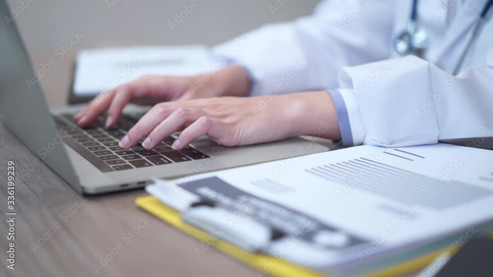 Part of doctor's hands typing on computer laptop keyboard Part of doctor's hands typing on computer laptop keyboard