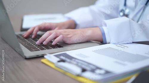 Part of doctor's hands typing on computer laptop keyboard