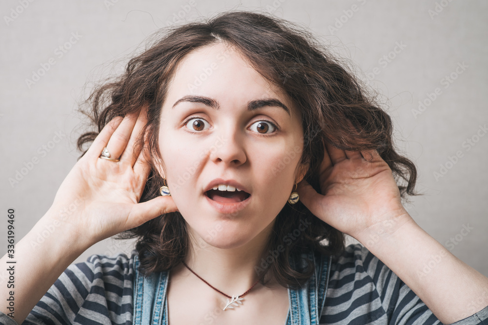 Woman with hand near ear can not hear. On a gray background. Woman with hand near ear can not hear. On a gray background.