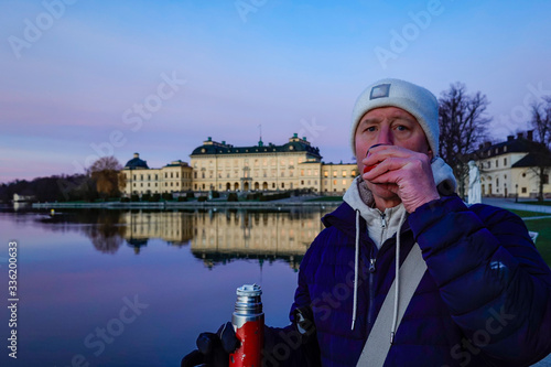 Photography Stockholm, Sweden A man drinks coffee at the Royal Palace from a thermos
