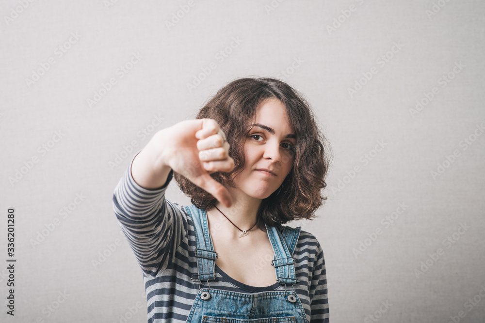 Woman showing thumb down. On a gray background. Woman showing thumb down. On a gray background.