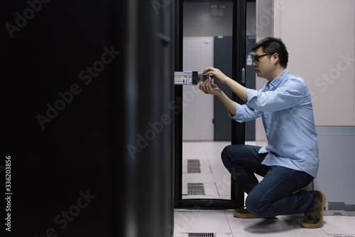 Server room technician inserting hard disk into server