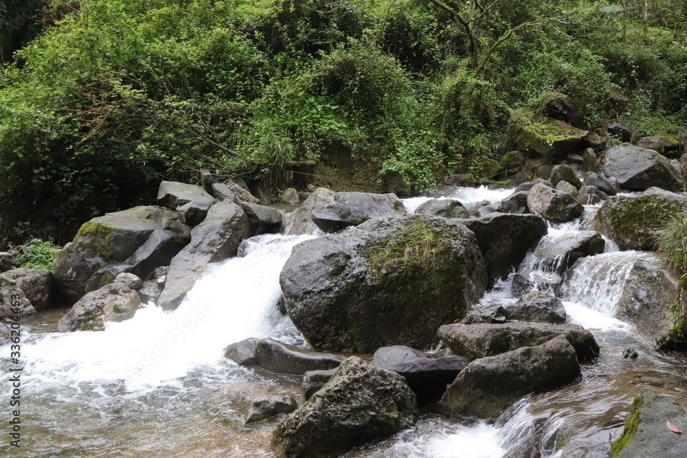 Beautiful landscape of cascade falls over mossy rocks, stones cover with moss, in a Mountain in Sichuan, China