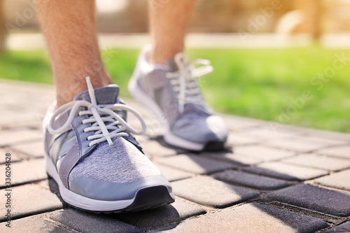 Sporty young man in training shoes outdoors on sunny day, closeup