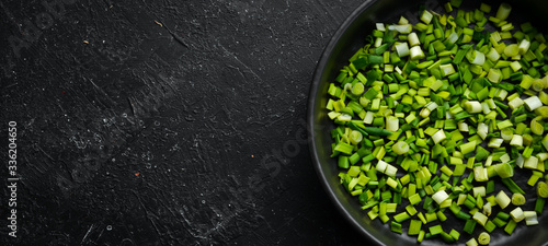 Fresh green sliced onion in a bowl. On a black background.