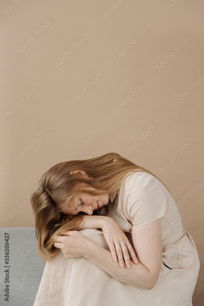 Portrait of beautiful woman wearing beige dress sitting on sofa. Portrait of beautiful woman wearing beige dress sitting on sofa.