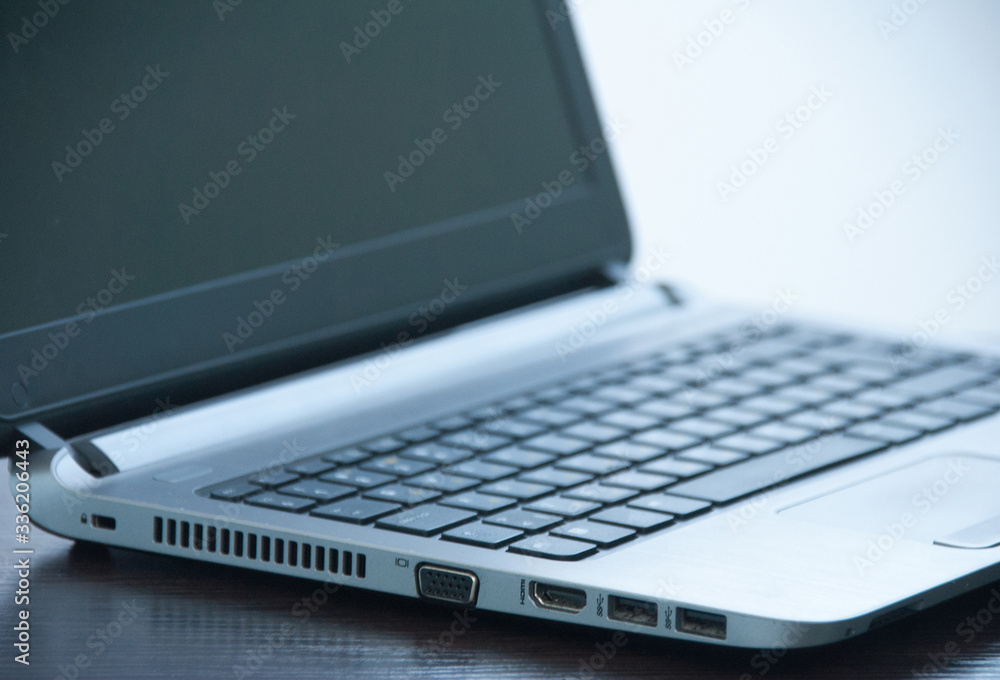 Silver laptop on a wooden table. Side view. VGA HDMI USB laptop port Silver laptop on a wooden table. Side view. VGA HDMI USB laptop port