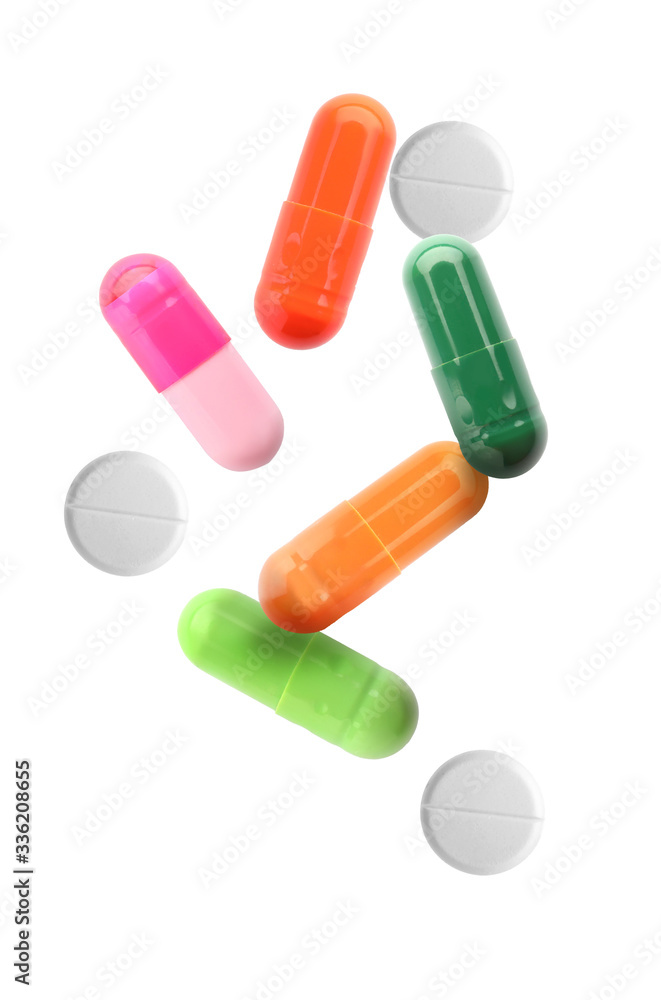 Different falling pills on white background