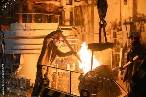 Men working with burning metal in foundry photo