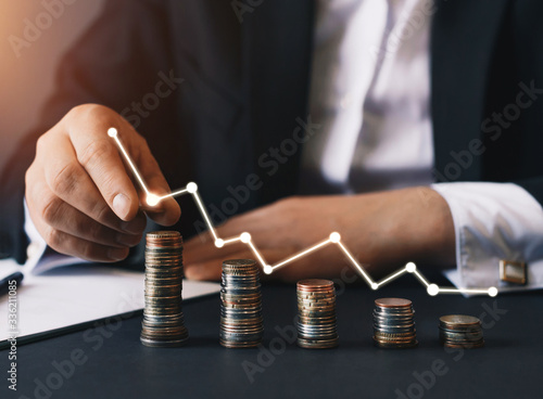 Businessman stacking coins with a graph of profit.