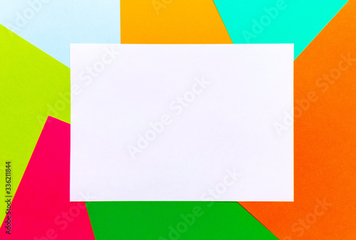 Flatlay of white blank sheet of paper mock up with a copy space on multicolored paper backgrounds. Top view, copy of space, selective focus