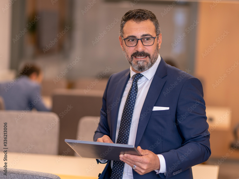 A smart-suited, bespectacled and saccid boss who controls both instant data and social media using his tablet as he wanders through the office A smart-suited, bespectacled and saccid boss who controls both instant data and social media using his tablet as he wanders through the office