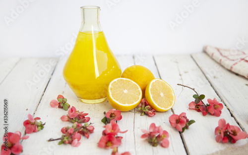 Lemon juice in a glass jug, lemons on an empty white background.