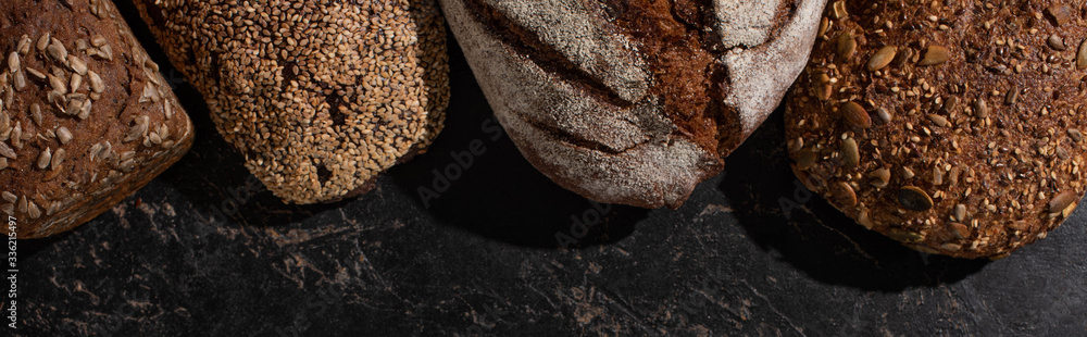 top view of fresh baked whole grain bread on stone black surface, panoramic shot top view of fresh baked whole grain bread on stone black surface, panoramic shot