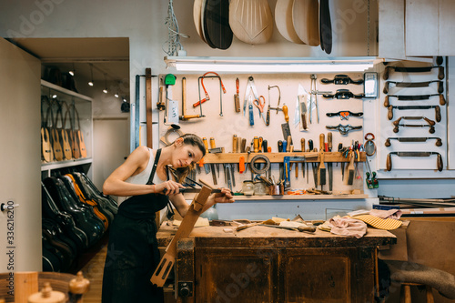 Young Woman Luthier working in handcrafted spanish guitar photo