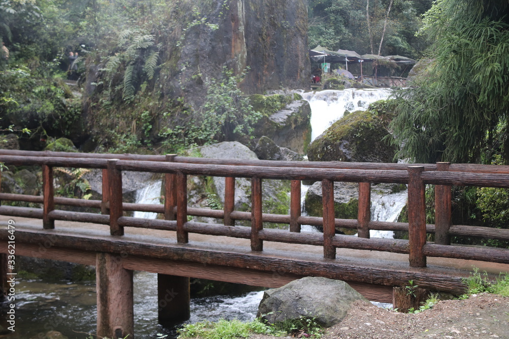 wooden bridge across a river in a mountain forest in Sichuan, China wooden bridge across a river in a mountain forest in Sichuan, China