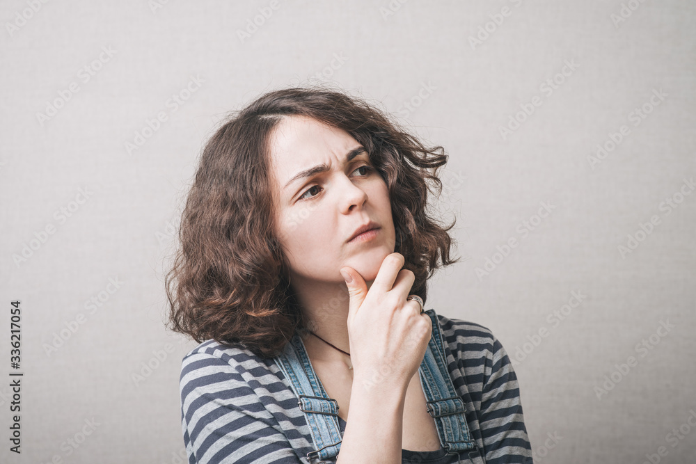 Girl thinking and holding his chin, wearing a jumpsuit