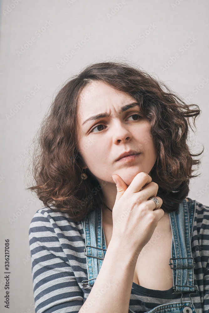 Girl thinking and holding his chin, wearing a jumpsuit Girl thinking and holding his chin, wearing a jumpsuit