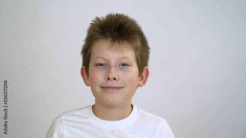 Handsome young guy with short blond hair in white t-shirt take off the disposable turquoise mask from his face with pleasure. Kid smile against a gray background. Corona virus healing concept. Handsome young guy with short blond hair in white t-shirt take off the disposable turquoise mask from his face with pleasure. Kid smile against a gray background. Corona virus healing concept.