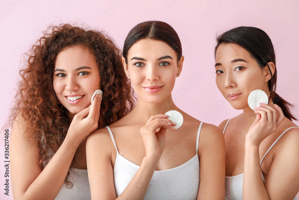 Beautiful young women with cotton pads on color background