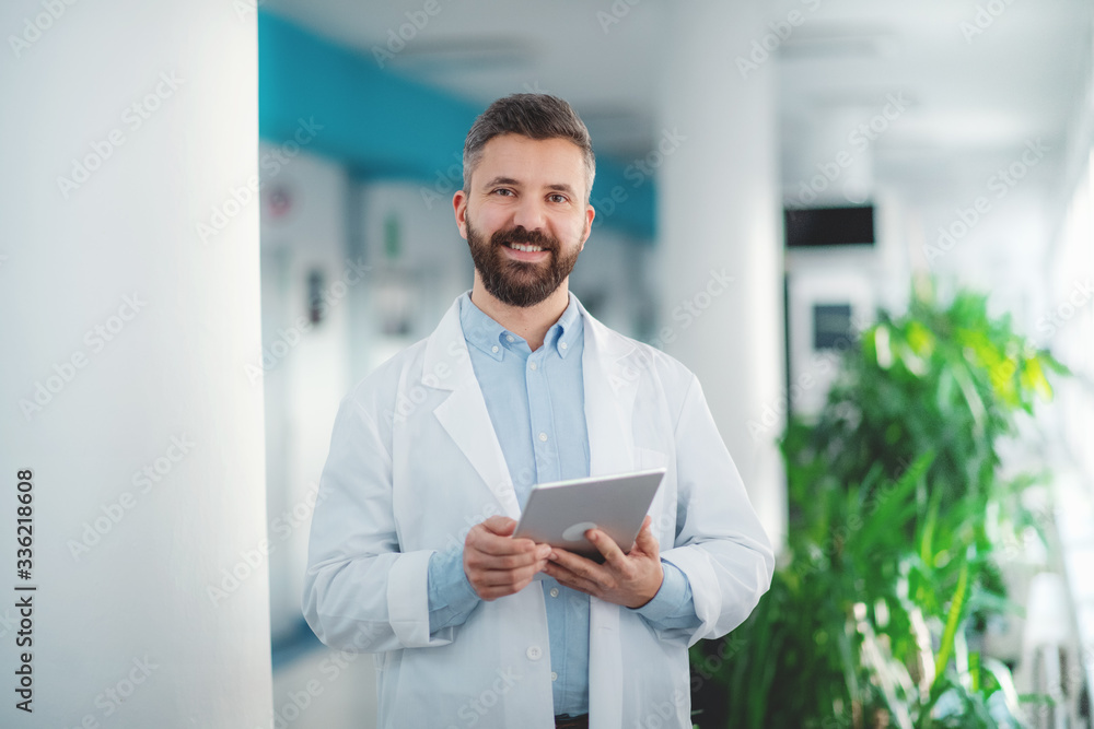 Portrait of man doctor standing in hospital, using tablet. Portrait of man doctor standing in hospital, using tablet.