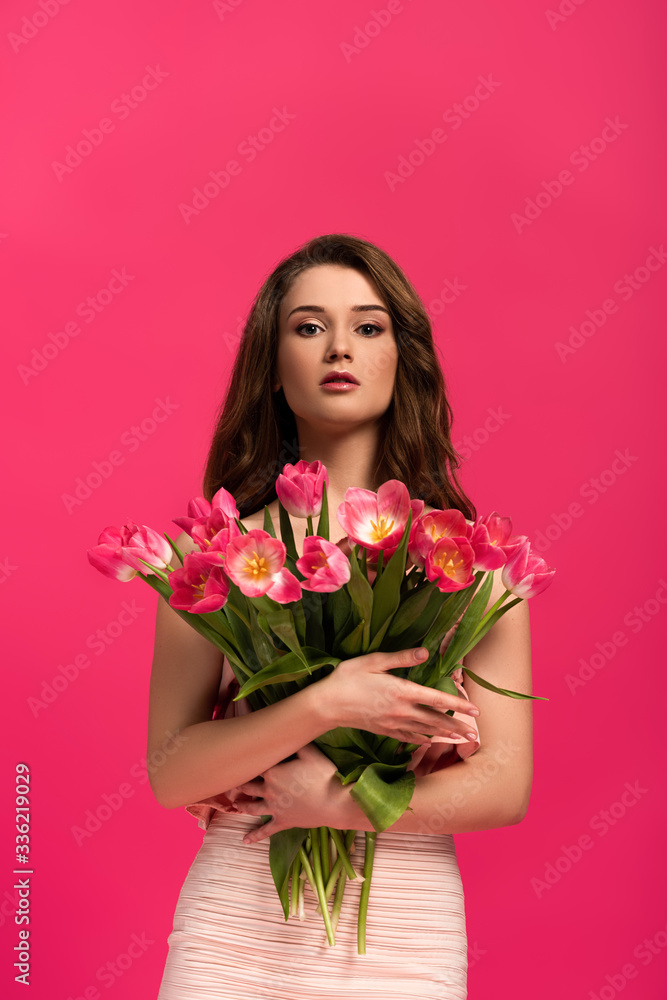 attractive girl holding bouquet of spring tulip flowers isolated on pink