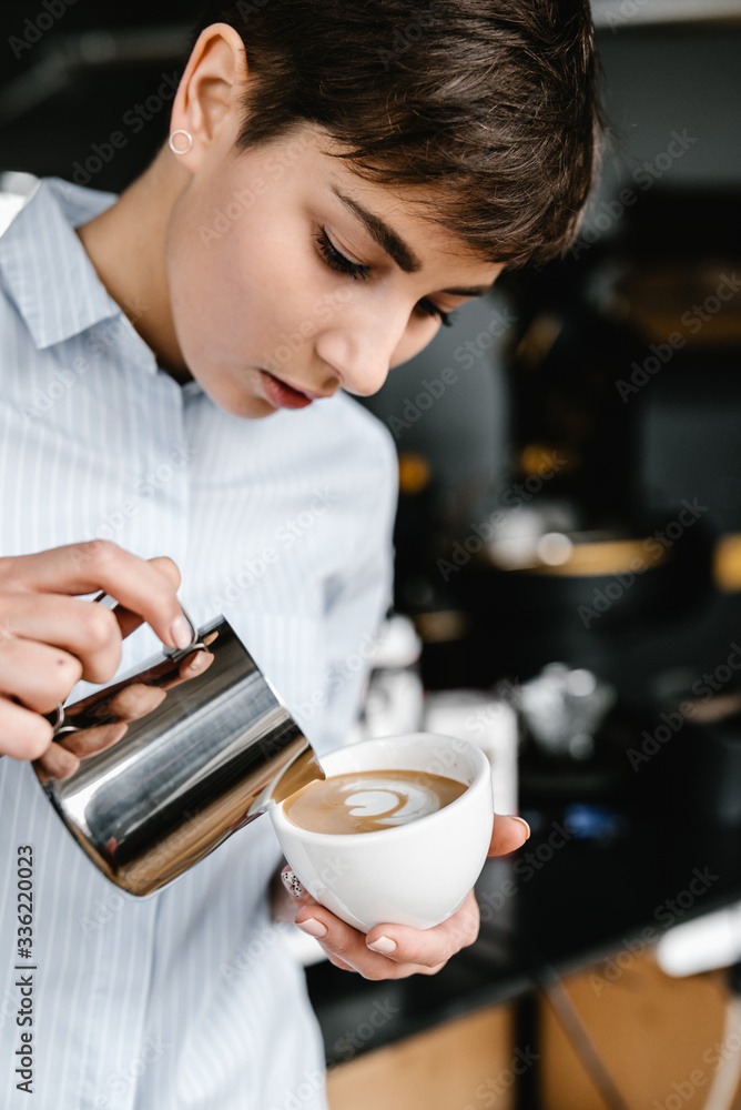 Female barista pouring milk from iron pitcher to cup. Female barista pouring milk from iron pitcher to cup.
