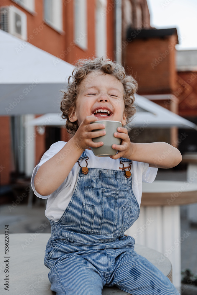 Cheerful kid holding cap and laughing Cheerful kid holding cap and laughing