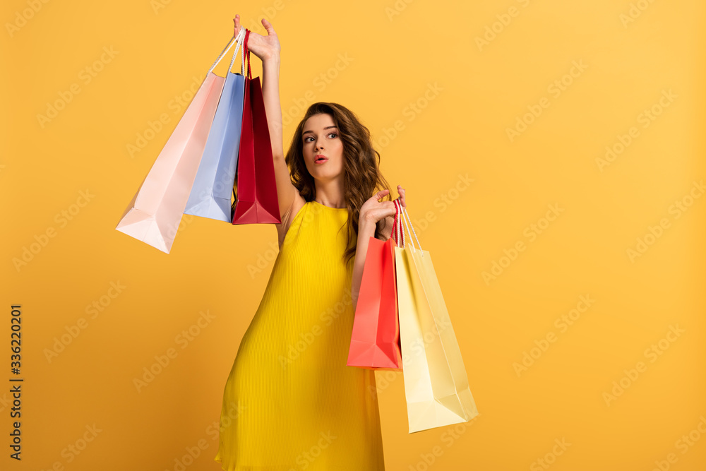 surprised girl in spring dress holding shopping bags on yellow