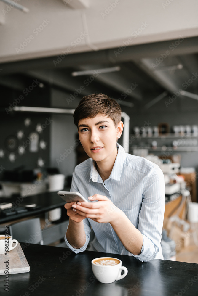 Brunette woman using smartphone, enjoying of cappuccino. Brunette woman using smartphone, enjoying of cappuccino.