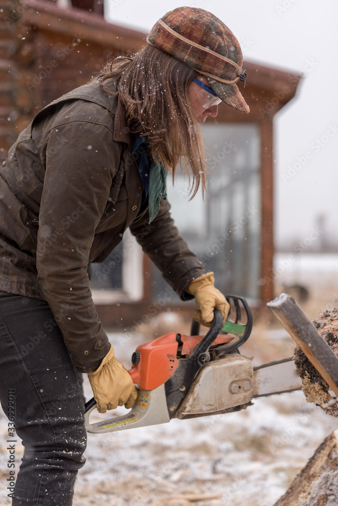 Ranch Manager and Cowgirl cutting wood with a chainsaw Ranch Manager and Cowgirl cutting wood with a chainsaw
