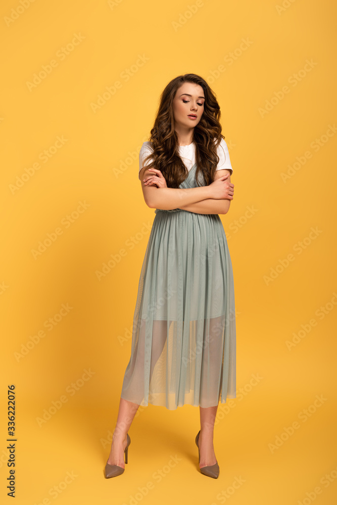 tender young spring woman with long hair and crossed arms on yellow tender young spring woman with long hair and crossed arms on yellow