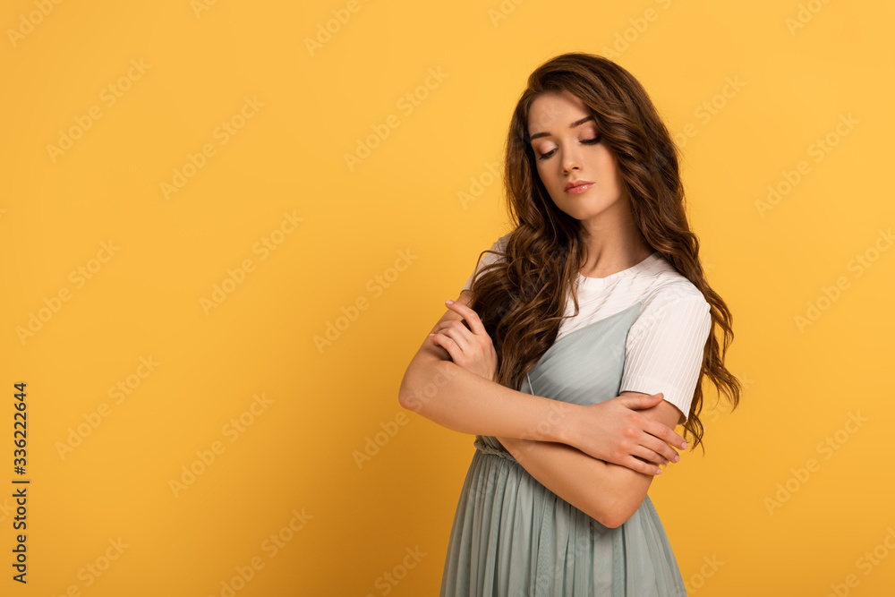 Obraz premium attractive tender girl with crossed arms on yellow