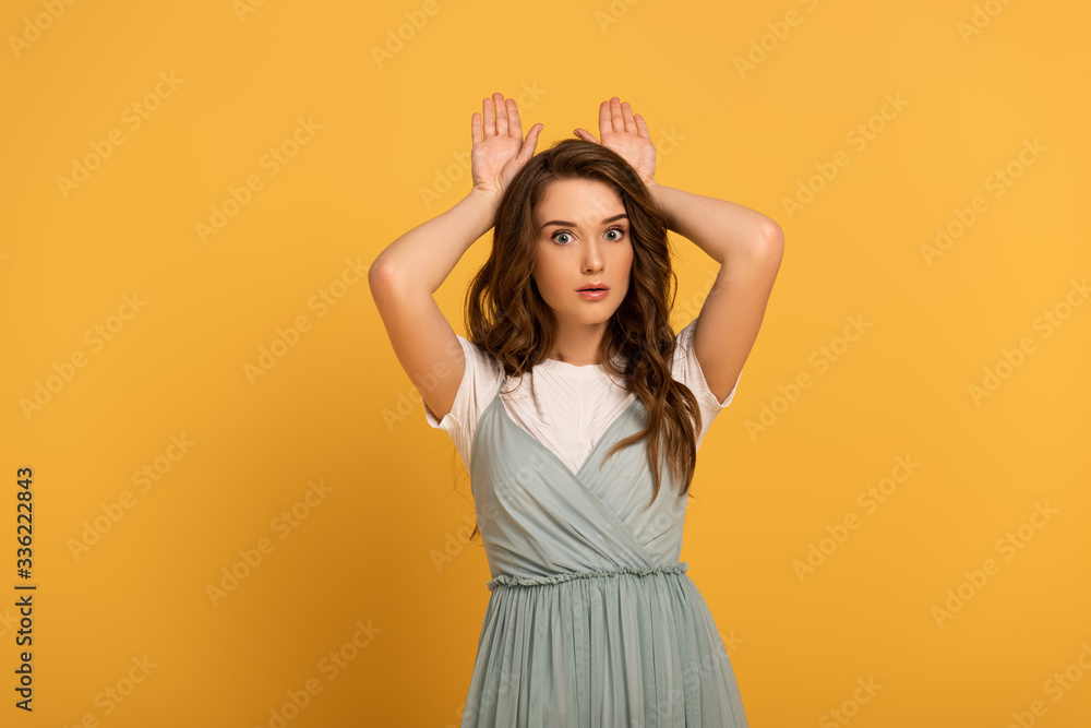 funny girl in making bunny ears on yellow funny girl in making bunny ears on yellow