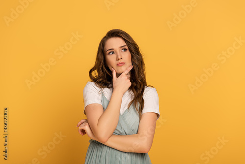 thoughtful spring woman with long hair isolated on yellow