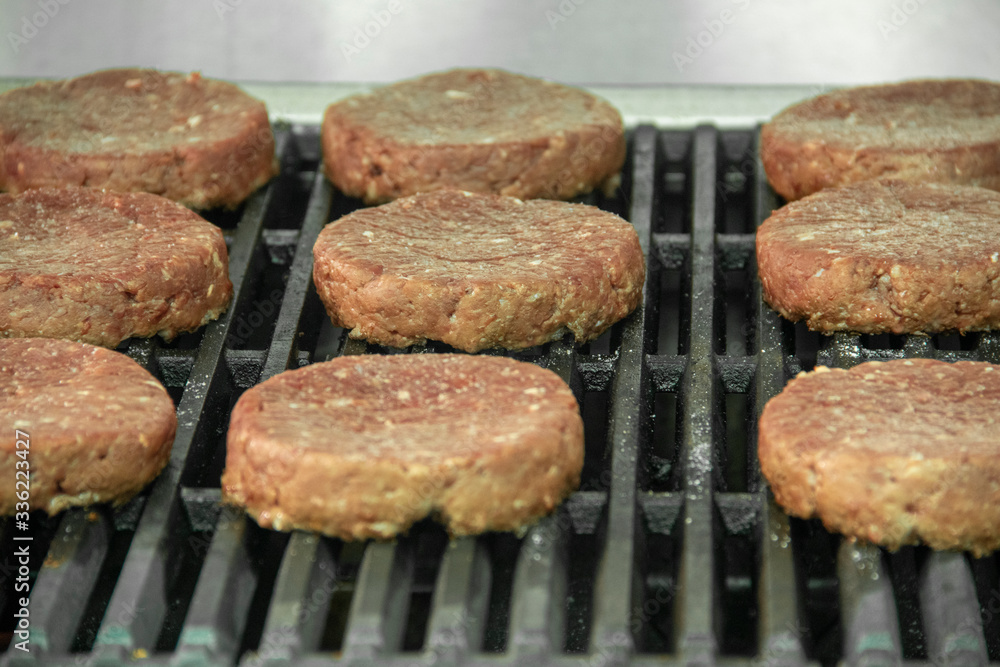 Raw hamburger patties organized on hot char broiler grill Raw hamburger patties organized on hot char broiler grill