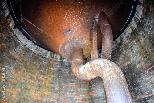 Water tank of old water tower. Rusty tank and pipes of the water system.