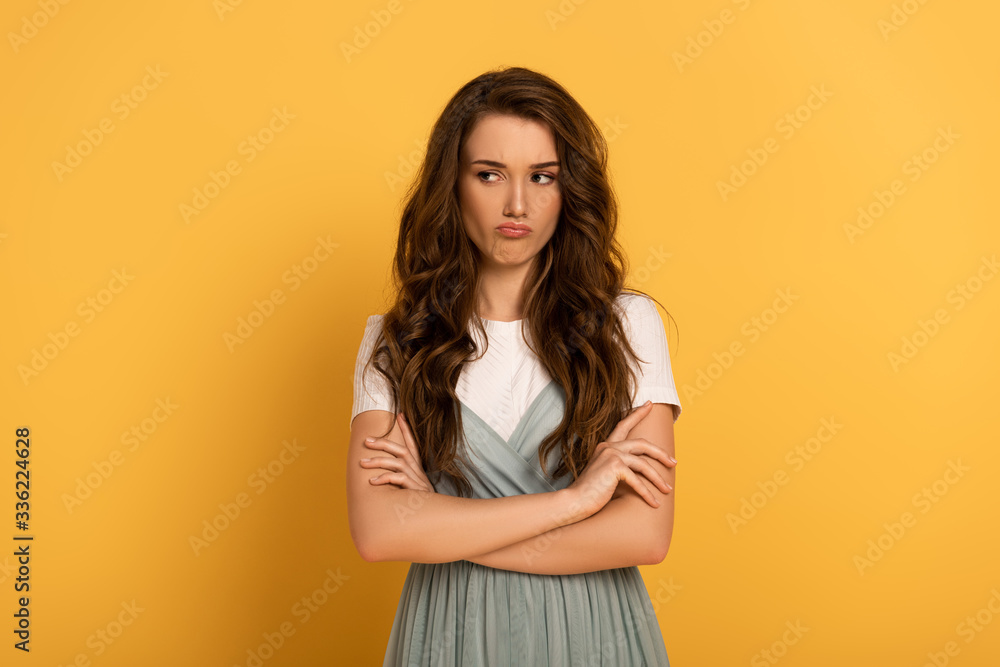 thoughtful young spring woman with crossed arms on yellow thoughtful young spring woman with crossed arms on yellow