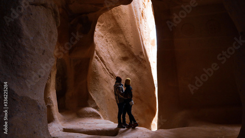 Travel couple standing into the cave surrounded by rock formations at Zelve Valley in Cappadocia, Turkey