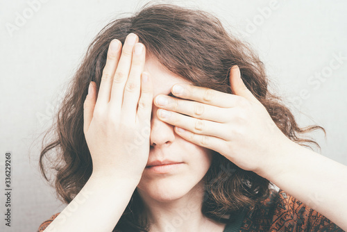 girl closes eyes with her hands