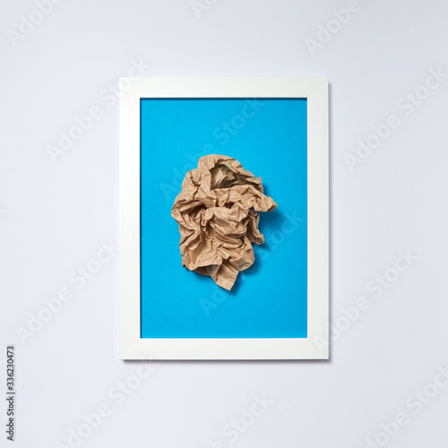 Crumpled sheet of paper in a blue frame on a light background photo