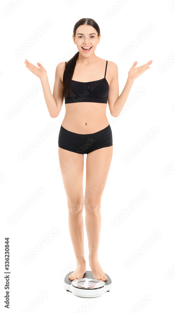 Happy young woman standing on scales against white background. Weight loss concept Happy young woman standing on scales against white background. Weight loss concept