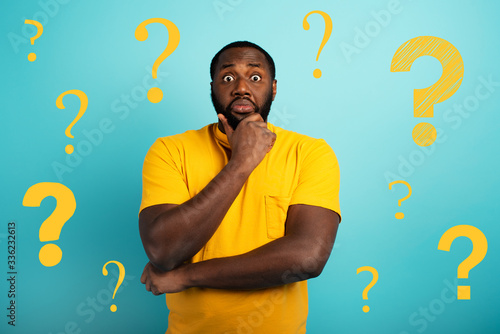Confuse and pensive expression of a boy with many questions . cyan colored background photo